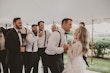 Bride and groom dancing under marquee with all the groomsmen smiling in background.