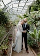 Bride wearing Bethany wedding dress by Rebecca Ingram with her husband inside a greenhouse