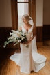 Bride wearing simple sheath wedding dress with V-neck.